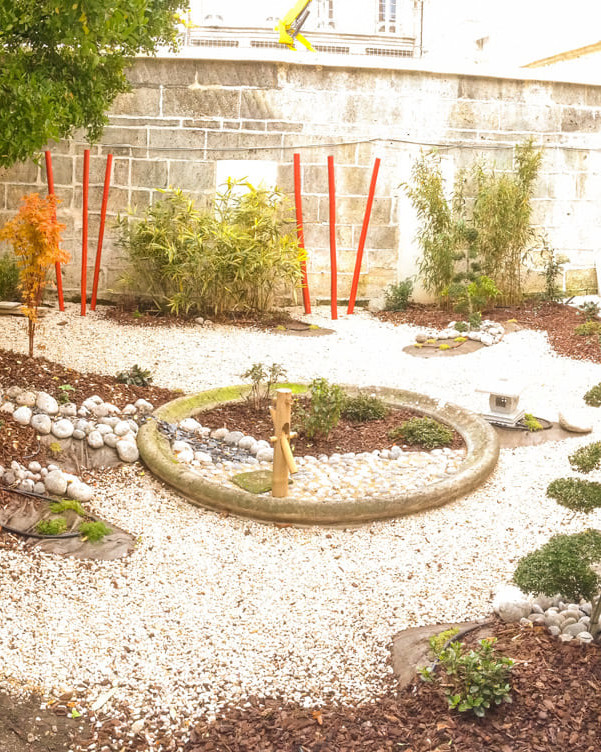 Jardin zen avec graviers et arbustes taillés.