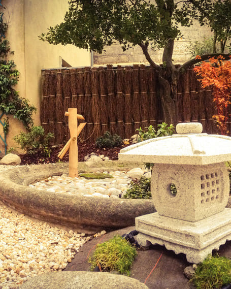 Jardin zen avec lanterne en pierre et bonsaï.